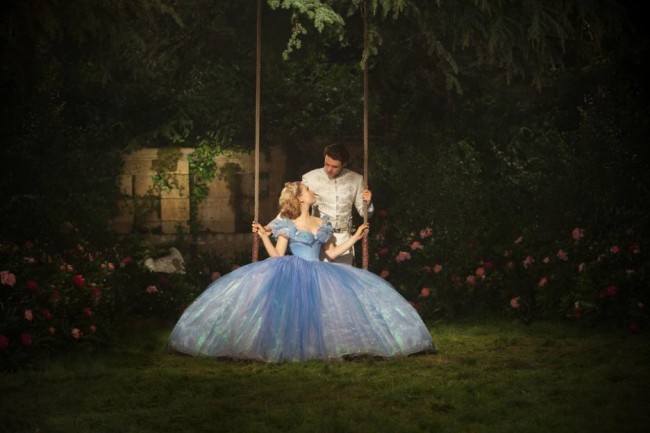 Prince Charming Richard Madden leaning over Cinderella Lily James on a swing 