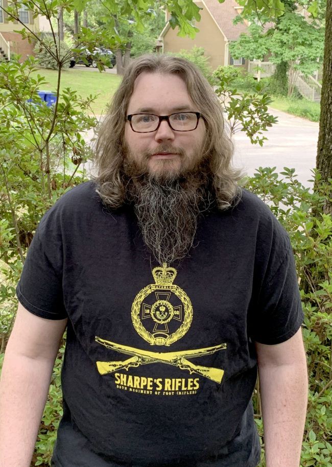 a man wearing a black tshirt with two crossed rifles stating sharpe's rifles from gifts from redbubble 